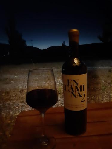 a bottle of wine next to a glass of wine at Cabañas Angualasto in Uspallata