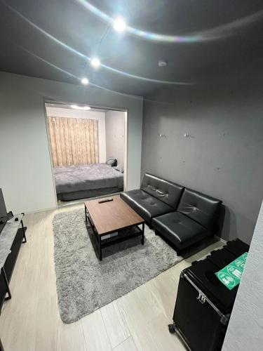 a living room with a black leather couch and a bed at Stellar西糀谷 301 in Tokyo