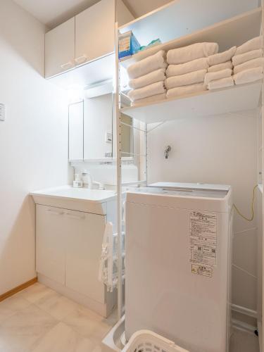 a white kitchen with a refrigerator and a sink at Familia Omorikaigan in Tokyo
