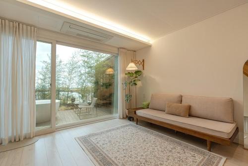 a living room with a couch and a large window at Jeju Byeolkkum Pension in Jeju