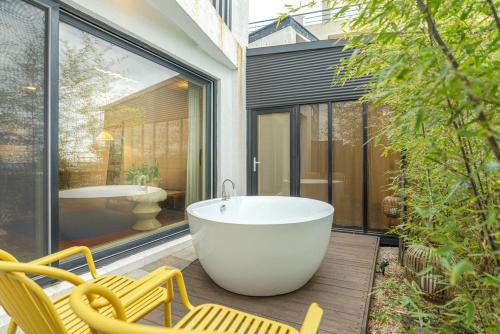 a bath tub sitting on a patio with two chairs at Jeju Byeolkkum Pension in Jeju