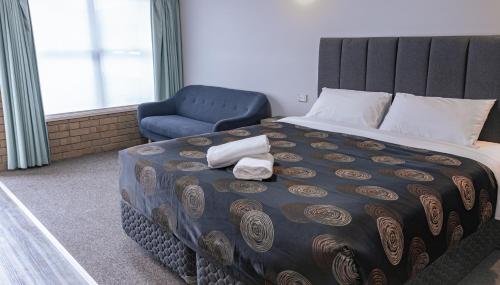 a bedroom with a bed and a blue chair at Tropicana Motor Inn in Cowes
