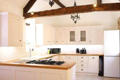 a kitchen with white cabinets and a white refrigerator at The Old Coach House in Witney
