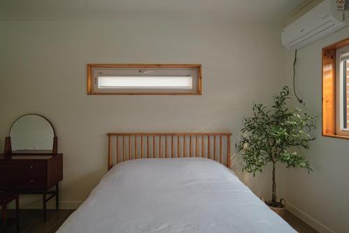 a bedroom with a bed and a window and a plant at Jeju Sin-eom-an-gil A in Jeju