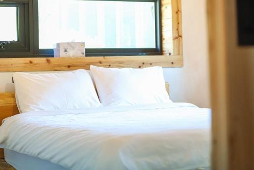 a bed with white sheets and pillows in a bedroom at Aewol Jokutti in Jeju