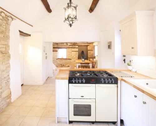 a kitchen with white cabinets and a stove at The Old Coach House in Witney