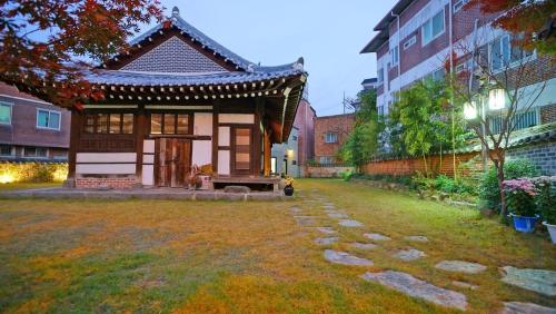 a small house in a yard next to a building at Pungryuheon Hanok private house in Jeonju
