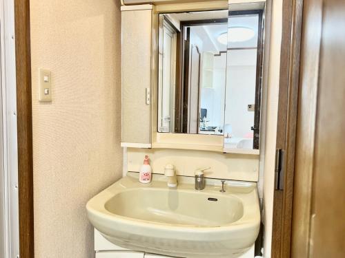 a bathroom with a sink and a mirror at 大国町駅徒歩3分 なんば駅1駅 最大6名 ロイヤル601 in Osaka