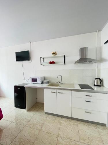 a white kitchen with a sink and a stove at Studio Aute in Papeete