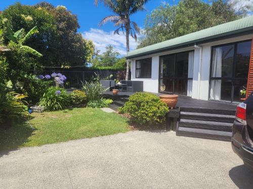 a house with a bench and plants in front of it at Peppertree in Tauranga