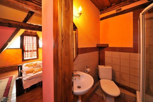 a bathroom with a sink and a toilet and a bed at Apartmány Village in Veľký Slavkov