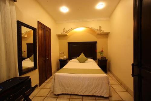 a bedroom with a bed and a large mirror at Hotel CasAntica in Oaxaca City