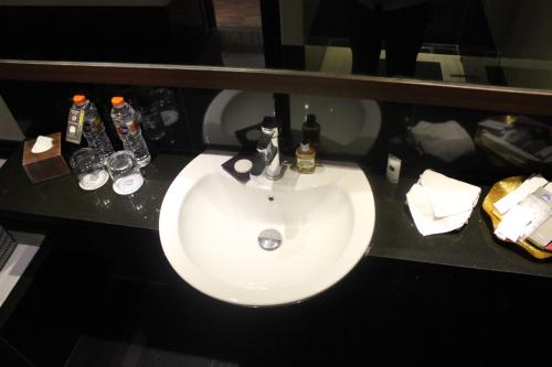 a white sink in a bathroom with bottles and glasses at Best Western Plus Makassar Beach in Makassar