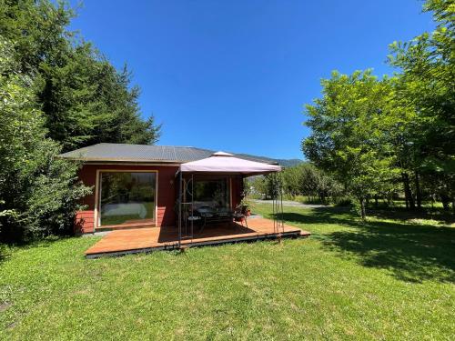 a small cabin with a deck in the grass at Comodidad y hermosa Vista Volcán in Melipeuco