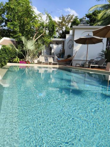a large swimming pool with an umbrella and chairs at O - HO Boutique Home in Baan Tai