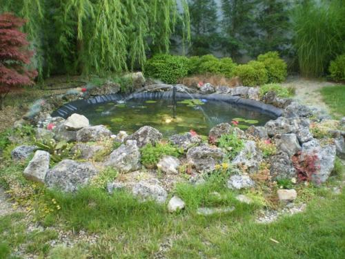 a pond in a garden with rocks and an umbrella at Familly Art Hotel Nirvana in Shumen