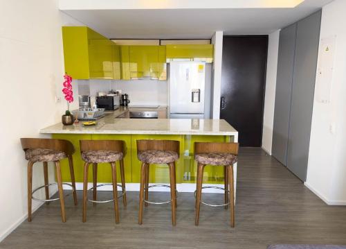 a kitchen with yellow cabinets and bar stools at Nuevo y Céntrico Apartamento in Bogotá