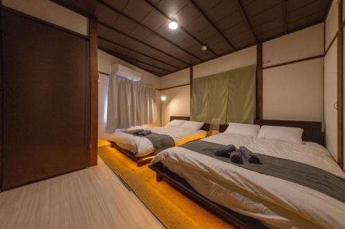 a bedroom with two beds and a large window at SORA usjまで電車で8分 5つの寝室 貸切の宿で楽しい時間を過ごしてください in Osaka