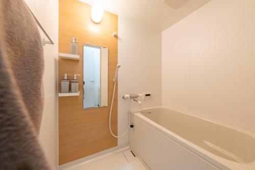 a bathroom with a bath tub and a mirror at SORA usjまで電車で8分 5つの寝室 貸切の宿で楽しい時間を過ごしてください in Osaka
