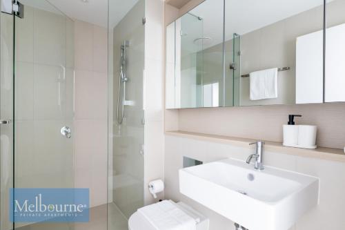 a white bathroom with a sink and a shower at Melbourne Private Apartments - Collins Wharf Waterfront, Docklands in Melbourne
