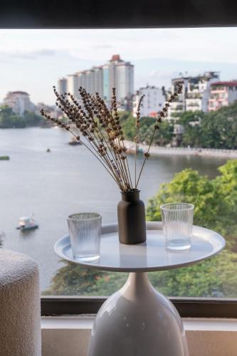 a table with two glasses and a vase with flowers on it at Aimee House Homestay Trấn Vũ in Hanoi