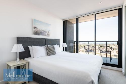 a bedroom with a white bed and a large window at Melbourne Private Apartments - Collins Wharf Waterfront, Docklands in Melbourne