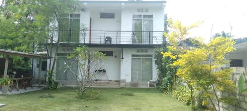a white house with a balcony on top of it at Sun Beach Villa in Weligama
