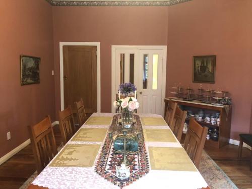 a dining room with a long table with flowers on it at English Cherry Tree Manor in Tamahere