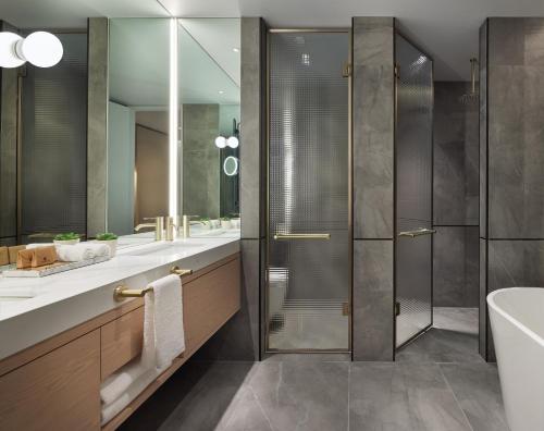a bathroom with a shower and a tub and a sink at Lanson Place Parliament Gardens in Melbourne