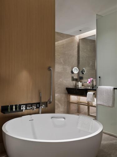 a bathroom with a large white tub and a sink at Hilton Shanghai Songjiang Guangfulin in Songjiang
