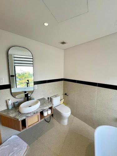 a bathroom with a sink and a toilet and a mirror at Aqua Blue Ocean View Condo - Free Swimming Pool in Hà My Tây (2)