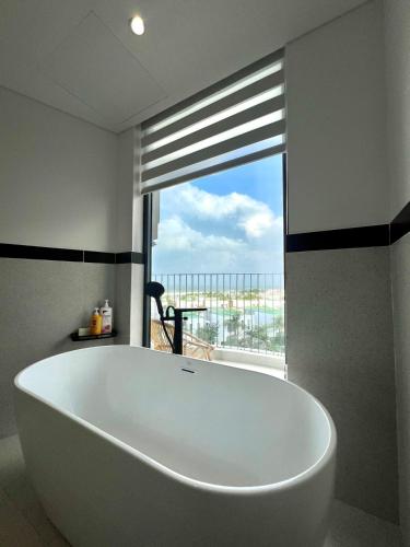 a large white tub in a bathroom with a window at Aqua Blue Ocean View Condo - Free Swimming Pool in Hà My Tây (2)