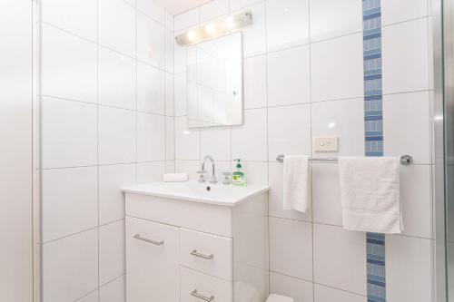 a white bathroom with a sink and a shower at Sawtell Beachside on 4th in Sawtell