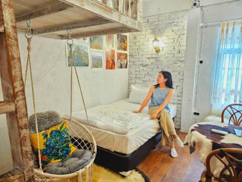 a woman sitting on a bed in a room at Silsopa Hostel in Nong Khai