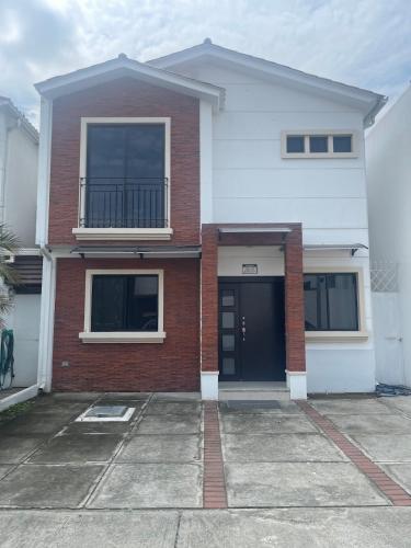 a white and red brick house with a black door at 3 dormitorios piscina privada BBQ parking free in SamborondÃ³n
