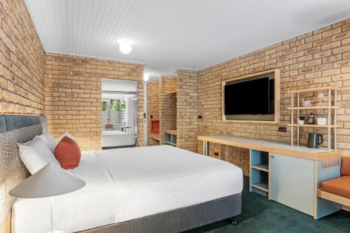 a bedroom with a white bed and a brick wall at Motel Flinders in Flinders