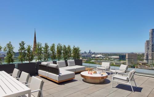 a patio with a couch and chairs on a roof at Lanson Place Parliament Gardens in Melbourne