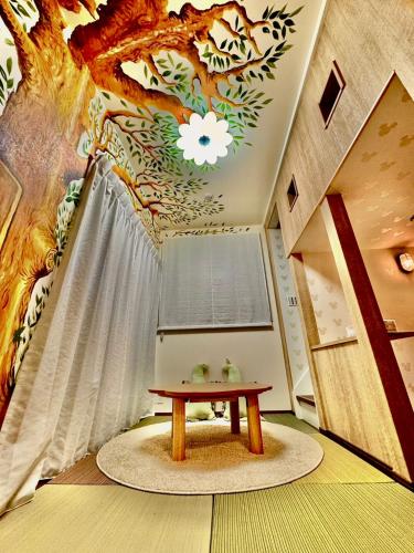 a room with a table and a painting on the ceiling at 8Home Kids House in Osaka