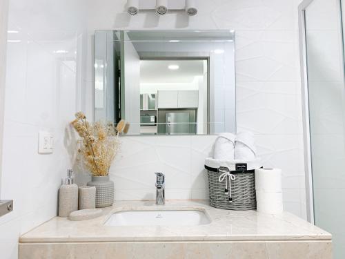 a bathroom sink with a mirror and a basket of towels at Airbnb Guayaquil, Mall del Sol, Piso alto in Guayaquil