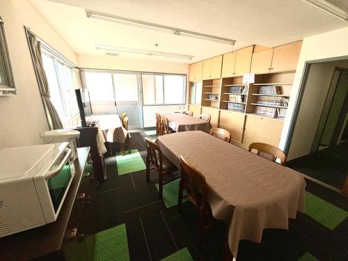 a dining room with tables and chairs and a kitchen at ビジネスホテル美咲 in Sakaide