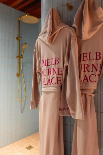 two shirts hanging on a rack in a bathroom at Hyde Melbourne Place in Melbourne