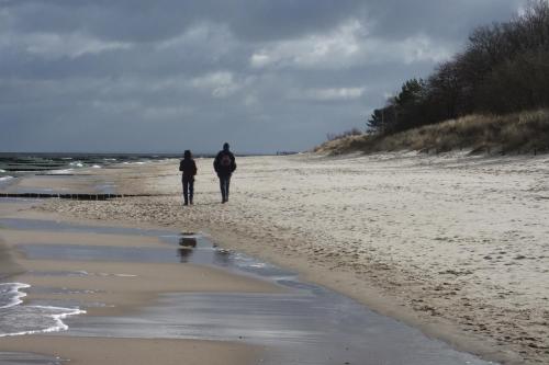 two people walking on a beach near the ocean at Hotel Wikinger in Zempin