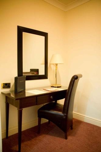 a desk with a mirror and a chair with a lamp at Park House Hotel in Shifnal