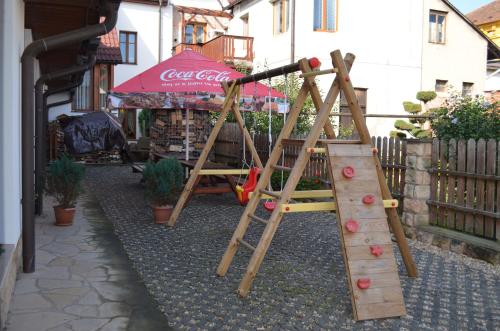 a wooden playground with a slide and an umbrella at Hotel u Kapra in Lázně Bělohrad