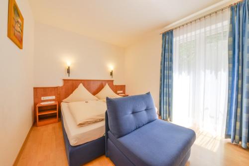 a bedroom with a bed and a blue chair at Hotel Waldhof in Hohenkammer