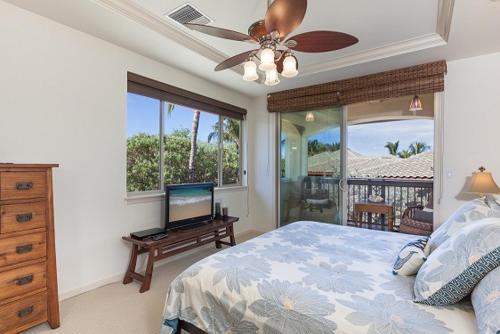 a bedroom with a bed with a ceiling fan and a television at 206 Fairways at Mauna Lani in Waikoloa