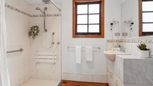 a white bathroom with a shower and a sink at Tasman Holiday Parks - Merool on the Murray in Echuca