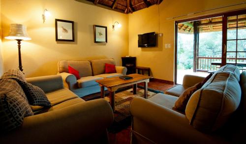 a living room with two couches and a table at Amafu Forest Lodge in Hoedspruit