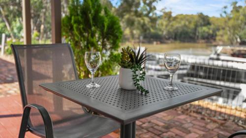 a table with two wine glasses and a potted plant at Tasman Holiday Parks - Merool on the Murray in Echuca