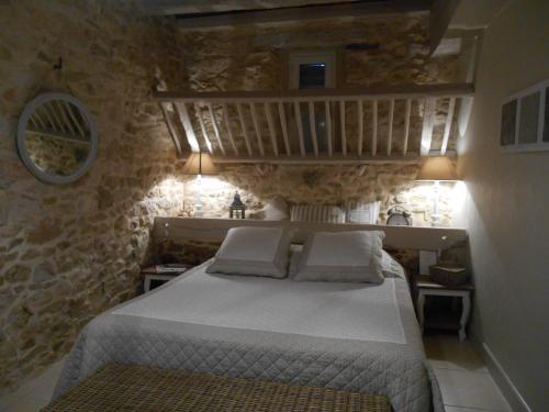 a bedroom with a bed in a stone wall at Les Chambres d'Hôtes du Rouyre in Réalmont